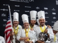 Team-USA-with-flag-statue-pan-TeamUSA_NOLA-546-photocredit_KenGoodman